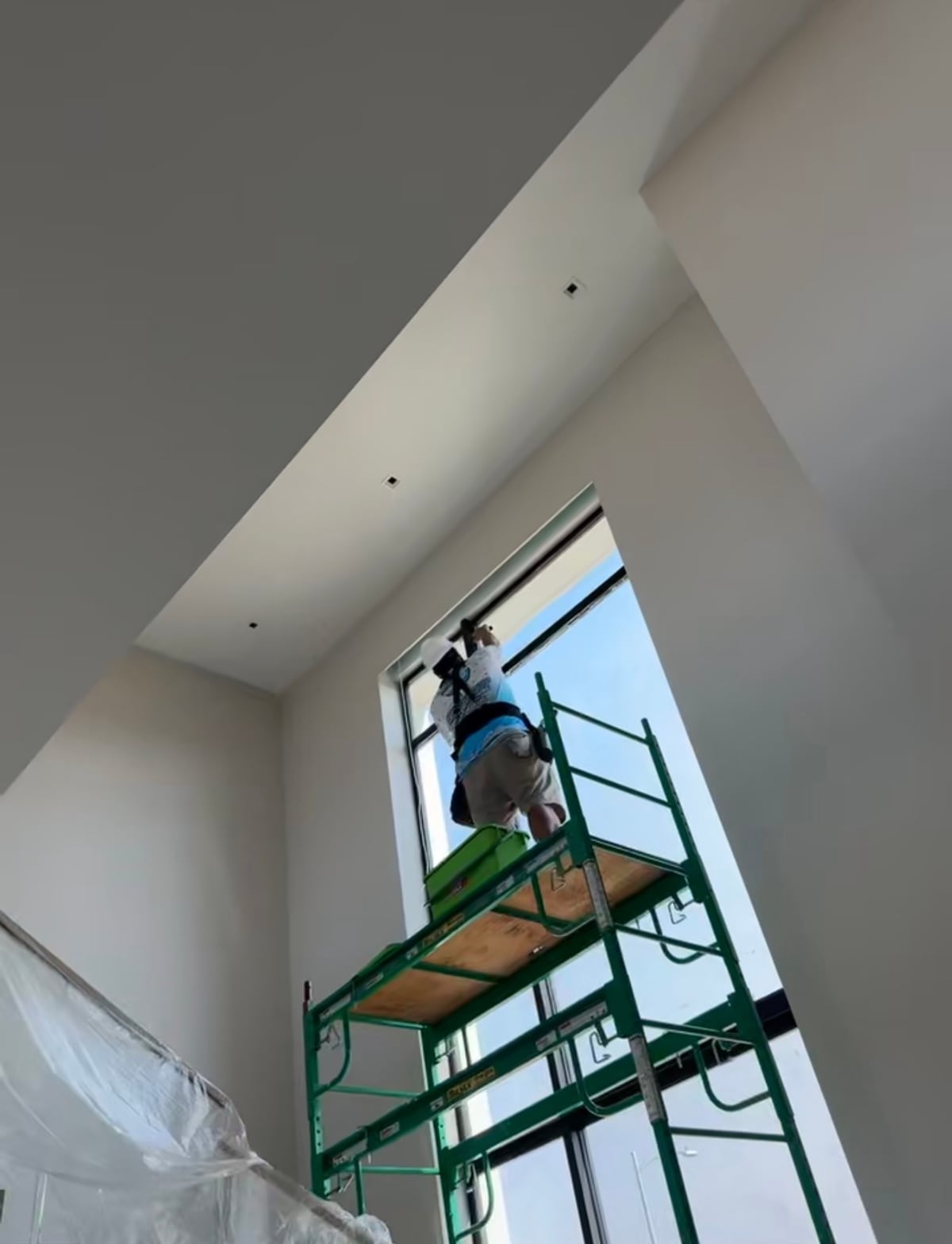 Scaffolding built on a staircase to reach a 20-foot window running up the vertical of a stair well