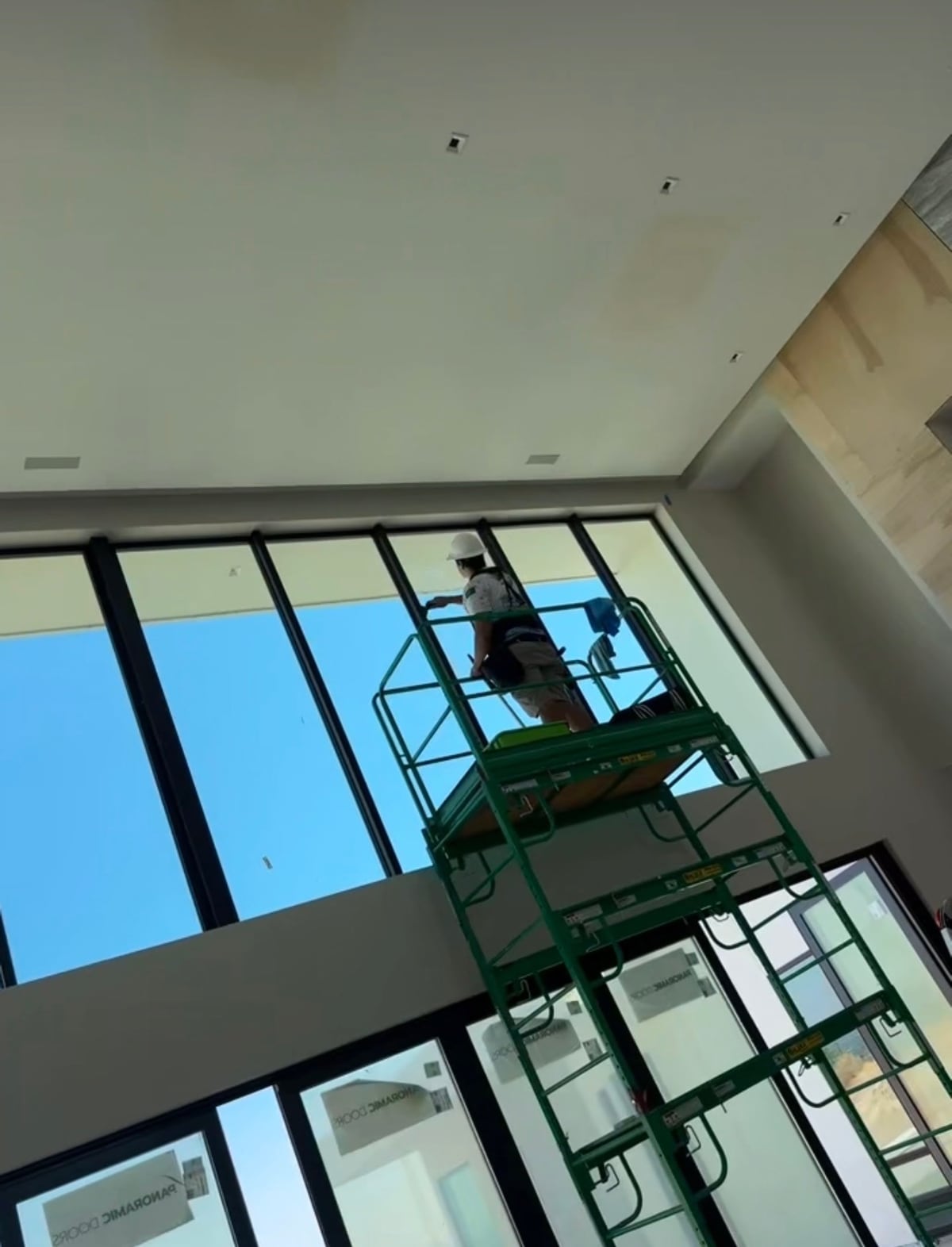 Scaffold tower built inside a vaulted-ceiling great room, protecting finished tile flooring while reaching 20-foot windows
